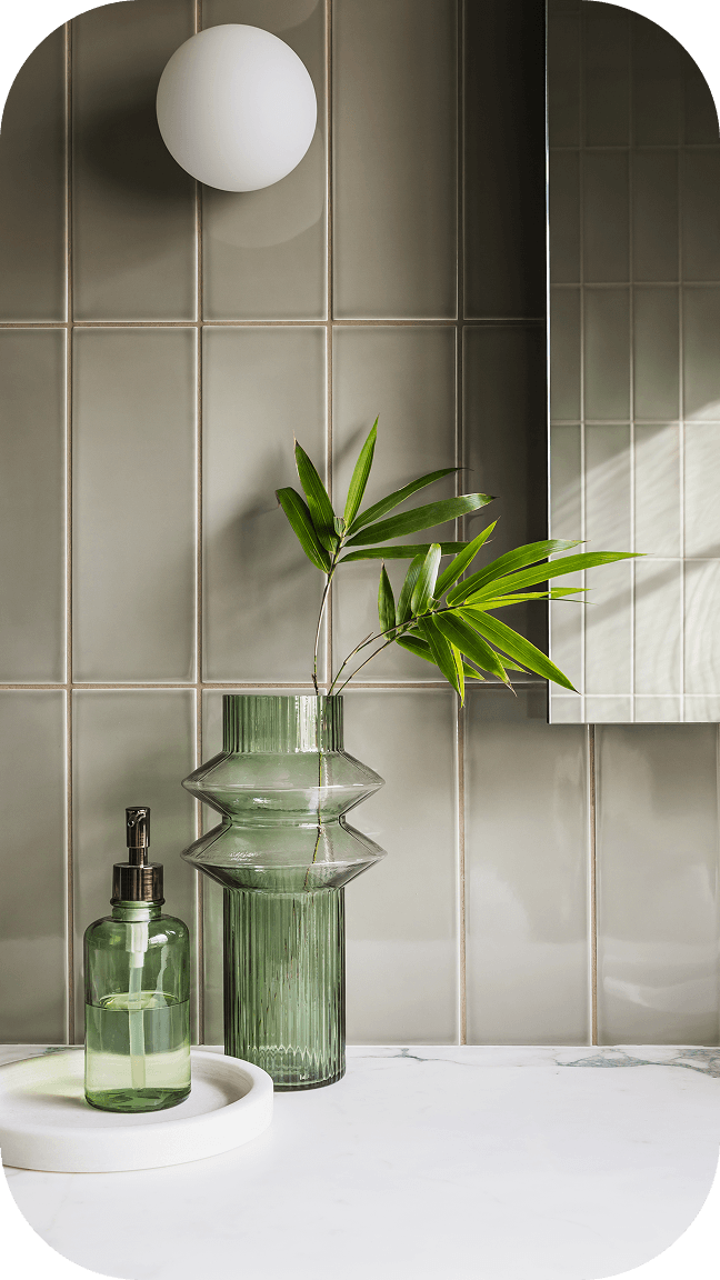 Modern minimalist interior with mirror, decorative glass vases, and plants on tiled wall